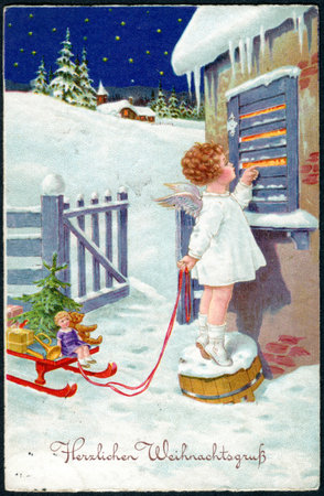 GERMANY - CIRCA 1930: A Christamas postcard printed in Germany, shows a little girl in the image of an angel with gifts. The inscription in German: Merry Christmas, circa 1930のeditorial素材