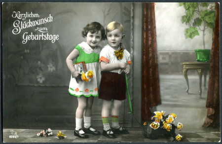 GERMANY - CIRCA 1914: A greeting postcard printed in Germany, shows a happy girl with a boy. The inscription in German: Happy birthday, circa 1914のeditorial素材