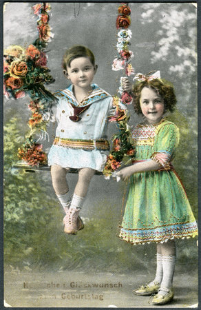 GERMANY - CIRCA 1914: A greeting postcard printed in Germany, shows a happy girl with a boy. The inscription in German: Happy birthday, circa 1914のeditorial素材