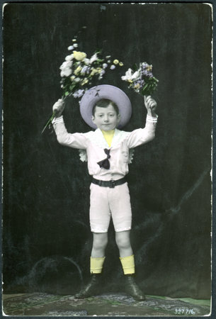 SWITZERLAND - CIRCA 1908: A postcard printed in Switzerland shows a boy with flowers, circa 1908のeditorial素材
