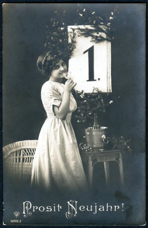 GERMANY - CIRCA 1916: A greeting postcard printed in Germany, shows a woman with a glass of...