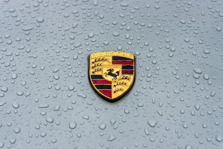 BERLIN - MAY 13, 2017: Hood emblem of sports car Porsche in raindrops on the grey background....