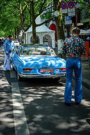 BERLIN - JUNE 17, 2017: Two men dressed in the style of the 70's look at Mercedes-Benz 220 SE....