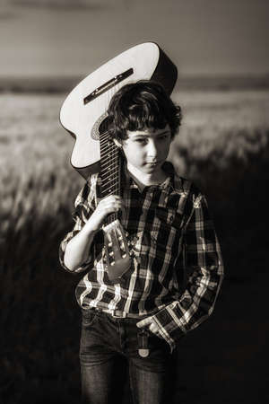 Boy with a guitar in nature. Sepia. Stylization.の写真素材