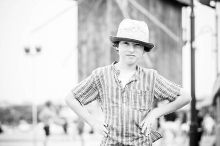 Portrait of a beautiful boy in a short shirt and hat on a blurred background. Black and white.の写真素材