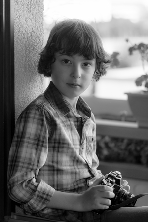 The boy is holding a vintage camera. Portrait. Black and white.の写真素材