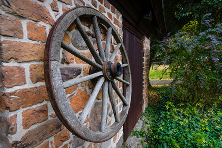 A wooden wheel from a cart hangs on a brick wall.の写真素材