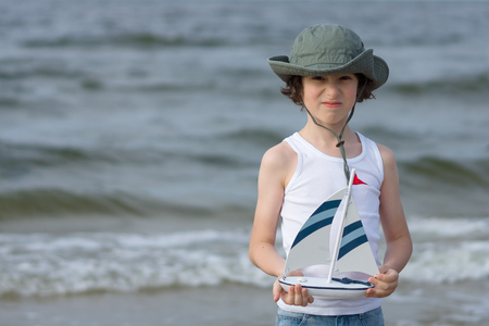 boy with a toy wooden ship playing on the seashore.の写真素材