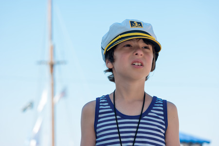 Portrait of a boy in a striped T-shirt and captain's cap.の写真素材