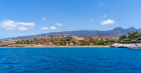 COSTA ADEJE, TENERIFE, CANARY ISLANDS, SPAIN - JULY 26, 2018: Hotels and houses on the popular coast of the resort. View from the ocean.のeditorial素材