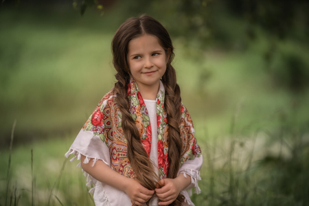 Portrait of a beautiful little girl with a scarf on her shoulders.の写真素材