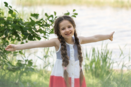 Portrait of a happy little girl on nature background.の写真素材