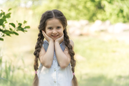 Portrait of a happy little girl on nature background.の写真素材