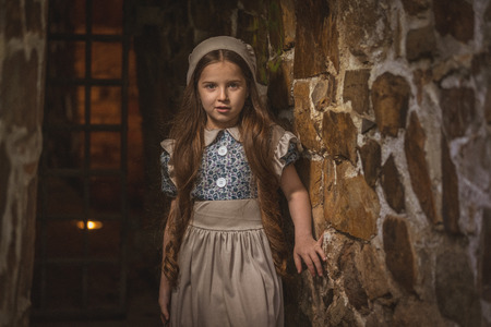 Frightened girl in the dungeons of an ancient castle. Stylization. Vintage toning.の写真素材