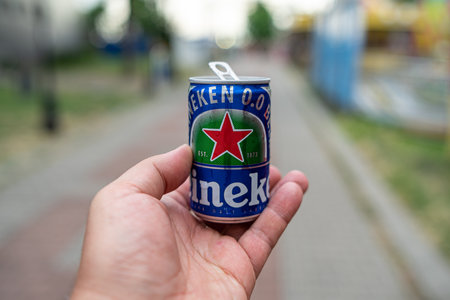 POMORIE, BULGARIA - JUNE 21, 2019: A small can of Heineken beer in male hands. Promotion on the street of the city. Free distribution of beer cans (only for adults). Shallow depth of field.のeditorial素材