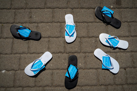 WARNEMUENDE (ROSTOCK), GERMANY - JULY 25, 2019: Flip flops lie on the pavement in a semicircle. Unusual advertising campaign shoe store.のeditorial素材