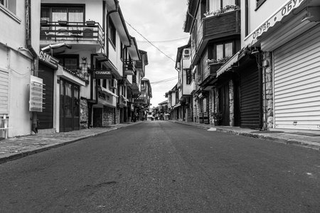 NESSEBAR, BULGARIA - JUNE 22, 2019: Beautiful and narrow street with restaurants, cafes and shops of the ancient seaside town. Deserted streets in the early morning. Black and white.のeditorial素材