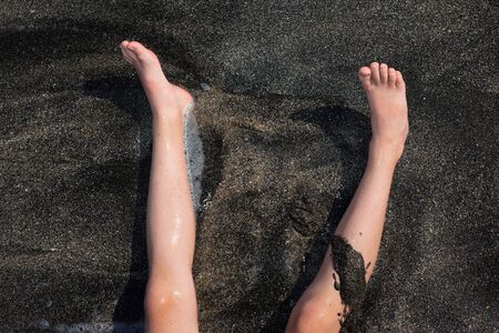 Children's feet on the sand, close-up.の写真素材