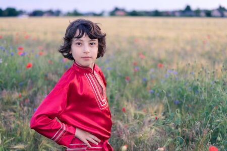 Portrait of a boy in a field with wild flowers. A boy dressed in Russian peasant shirt.の写真素材