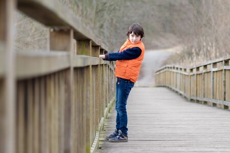 Portrait of a handsome boy standing on a wooden bridge.の写真素材