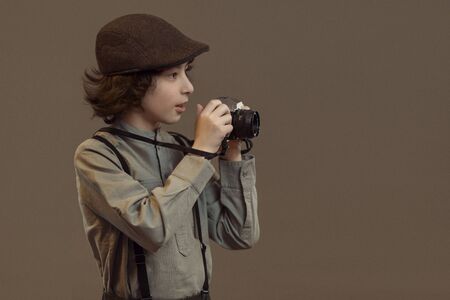 Portrait of a joyful boy in retro style. In his hands is a camera. Vintage stylization.