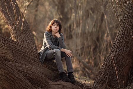 Portrait of a handsome fashionable boy, dressed in jeans and a knitted sweater on a background of nature.の写真素材