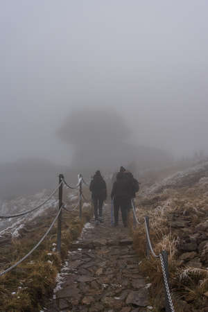 KARPACZ, POLAND - OCTOBER 16, 2021: Tourists climb Poland's popular mountain peak - Sniezka in the Giant Mountains in cloudy weather. In the background, the building of the meteorological observatory.のeditorial素材