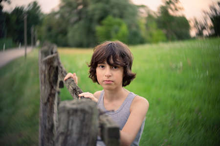 Rural portrait of a boy near a wooden fence.の写真素材