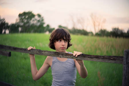 Rural portrait of a boy near a wooden fence.の写真素材