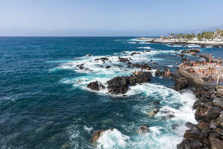 PUERTO DE LA CRUZ, TENERIFE, SPAIN - JULY 14, 2021: City promenade and beach with vacationers.のeditorial素材
