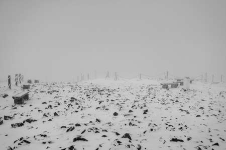 Frost-covered frozen wooden benches. Winter landscape. Black and white.