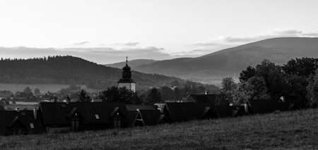Autumn landscape. Early foggy morning in the foothills. The roofs of village houses and the dome of the church. Black and white.の写真素材