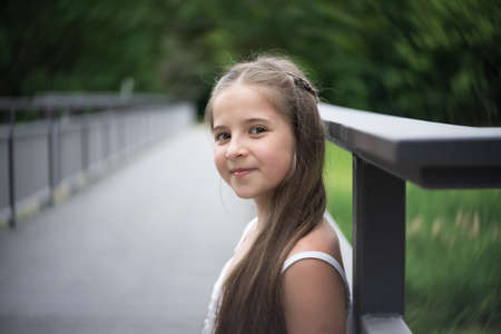 Portrait of a beautiful girl with long hair standing on a bridge.の写真素材