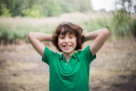 Portrait of a boy on the background of nature. Surprised and joyful grimace.の写真素材