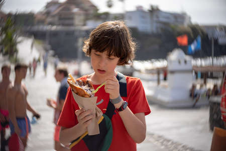 A teenager eats a bubble waffle on the promenade of Puerto de la Cruz. Tenerife. Canary Islands. Spain.の写真素材