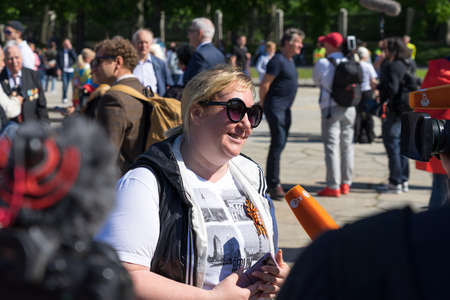 BERLIN - MAY 09, 2022: Victory Day in Treptower Park. A visitor to the war memorial gives an interview to journalists from the German television company ZDF.のeditorial素材