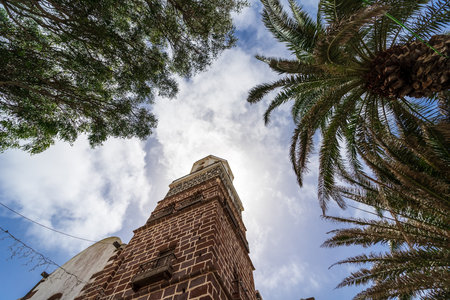 Bell tower of Nuestra Senora de Guadalupe church against the background of the sky and palm branches. Teguise village. Lanzarote. Canary Islands. Spain.の写真素材
