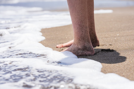 Children's feet on the sand, close-up.の写真素材