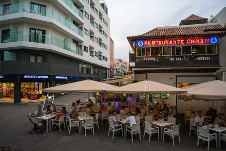 PUERTO DE LA CRUZ, SPAIN - JULY 19, 2023: Shopping street and an open-air restaurant on the historic center of a popular tourist town on the island of Tenerife, Canary Islands.のeditorial素材