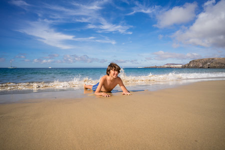 Portrait of a teenager lying on the sandy shore of the ocean.の写真素材