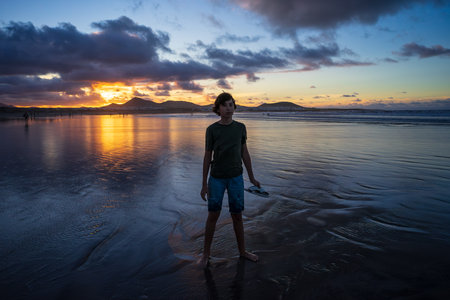 Portrait of a teenager on the evening's Famara Beach (Playa de Famara) -  popular surfing beach in Lanzarote. Canary Islands. Spain.の写真素材