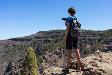 A teenager uses a three-axis image stabilizer to film a natural mountain landscape on a smartphone camera. Gran Canaria. Canary Islands. Spain.の写真素材