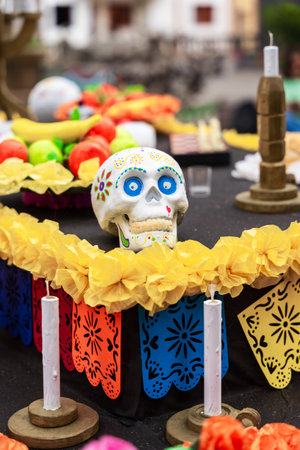 GARACHICO, TENERIFE - AUGUST 5, 2025: Decorated skull on colorful festival altar with fruits, candles and papel picado during Fiesta de la Muerte, Canary Islands.のeditorial素材
