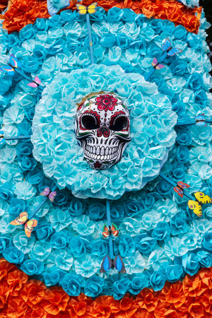 GARACHICO, TENERIFE - AUGUST 5, 2025: Decorative skull mask surrounded by blue paper flowers and colorful butterflies during Fiesta de la Muerte street celebration. Canary Islands.のeditorial素材