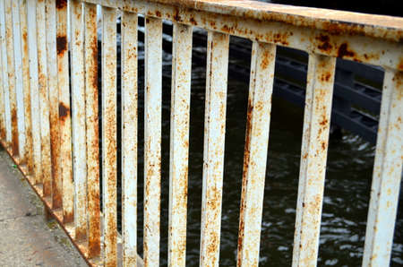 rusted white handrail of a bridge at the waterの写真素材