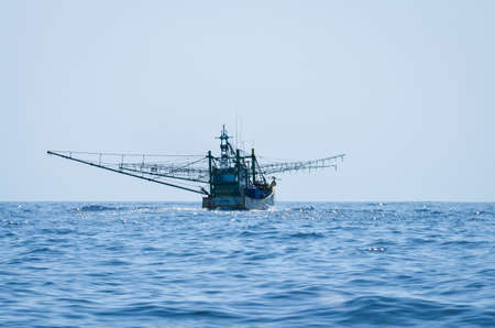 blue Fishing trawler on the ocean water aloneの写真素材