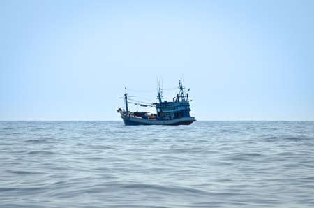 blue Fishing trawler on the ocean water aloneの写真素材