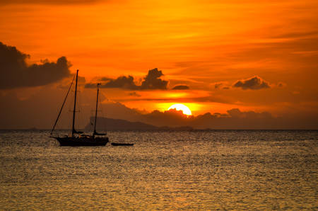 dramatic tropical sunset with silhouette of boatの写真素材