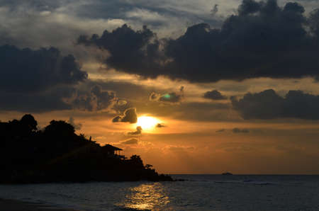tropical sunset with wooden hut and palmtree at coast