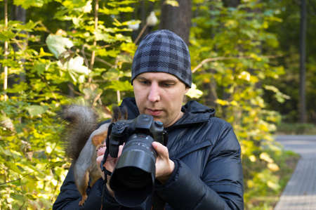 The photograph depicts a male photographer with a squirrelの写真素材